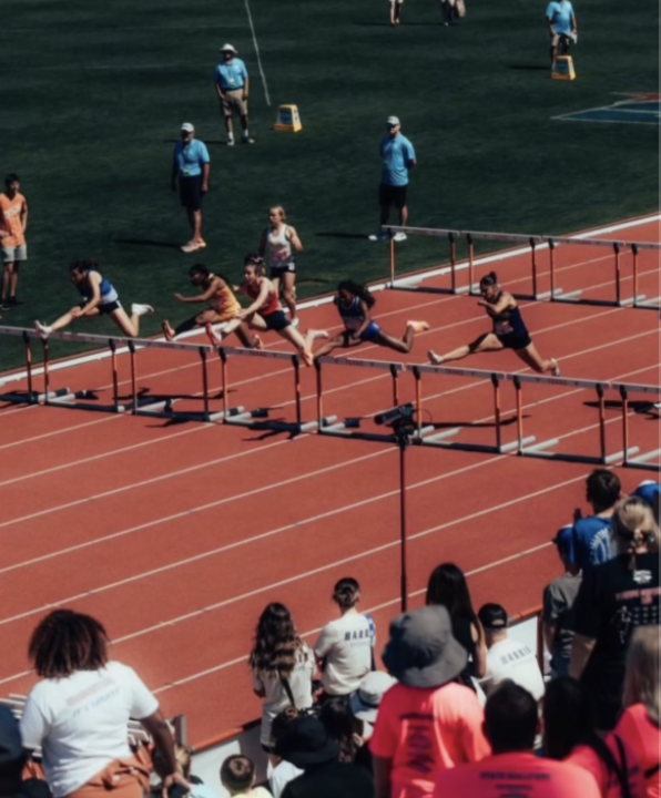 The middle of an intense 100m hurdle race at the University of Texas track and field stadium. 